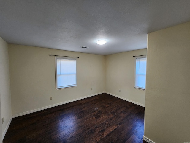 spare room with a textured ceiling and dark wood-type flooring