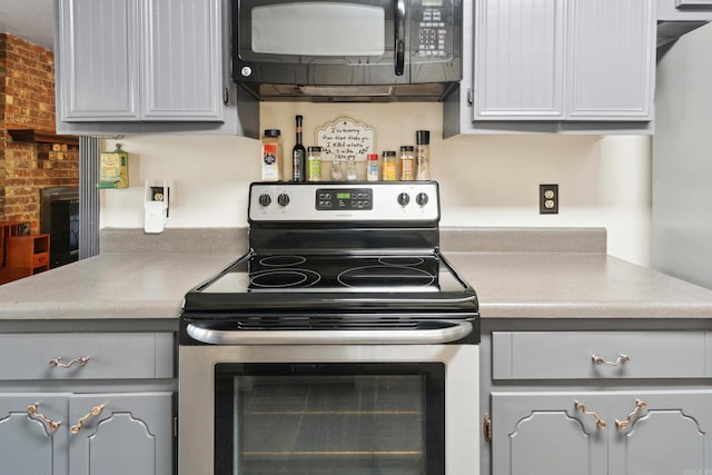 kitchen with brick wall, stainless steel electric range, and gray cabinets