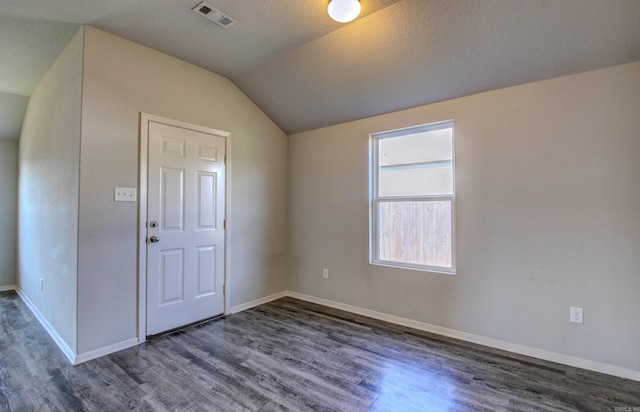 foyer entrance with a textured ceiling, lofted ceiling, and dark hardwood / wood-style floors