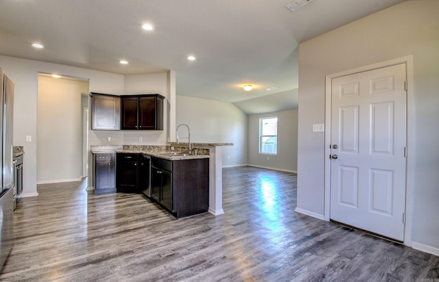 kitchen with light stone countertops, sink, dark brown cabinets, kitchen peninsula, and hardwood / wood-style flooring