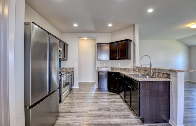 kitchen featuring kitchen peninsula, appliances with stainless steel finishes, light hardwood / wood-style flooring, dark brown cabinetry, and sink