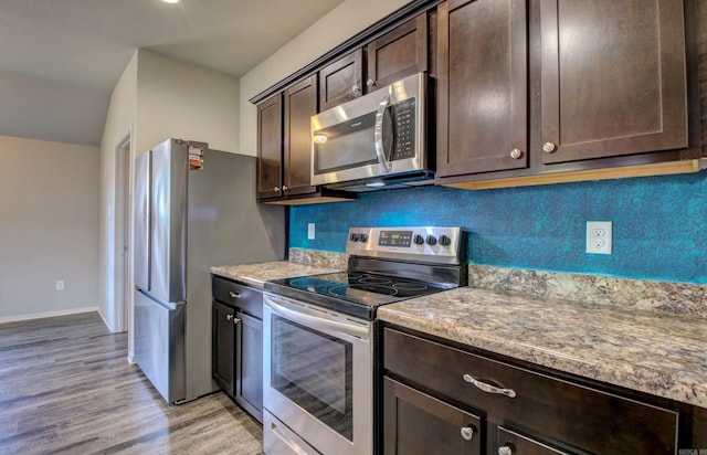 kitchen featuring tasteful backsplash, stone countertops, dark brown cabinets, stainless steel appliances, and light hardwood / wood-style flooring