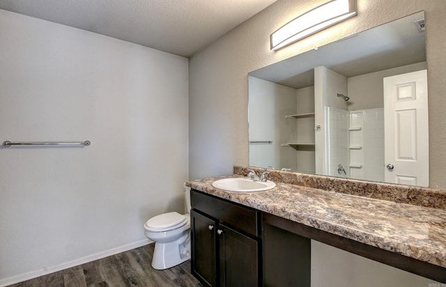 bathroom with wood-type flooring, a textured ceiling, toilet, walk in shower, and vanity