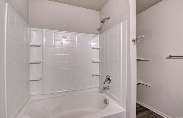 bathroom with a textured ceiling, hardwood / wood-style floors, and tiled shower / bath