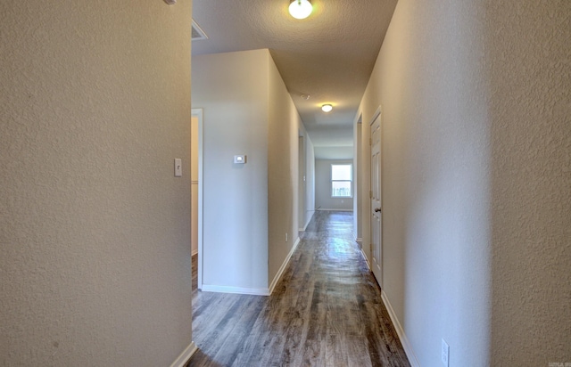 corridor featuring a textured ceiling and dark hardwood / wood-style floors