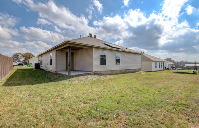 back of property with a patio, central air condition unit, a yard, and a trampoline