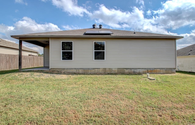 rear view of property with a yard and solar panels