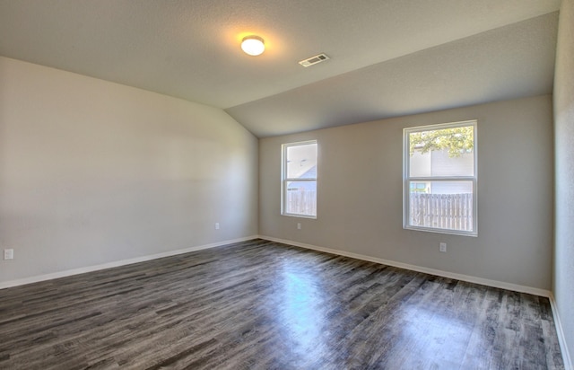 spare room with lofted ceiling, a textured ceiling, and dark hardwood / wood-style floors