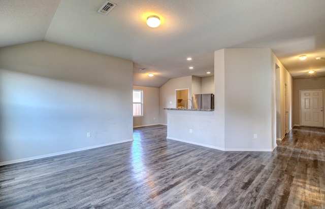 unfurnished living room with a textured ceiling, vaulted ceiling, and dark hardwood / wood-style floors