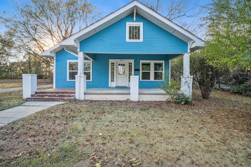 bungalow with a porch and a front lawn