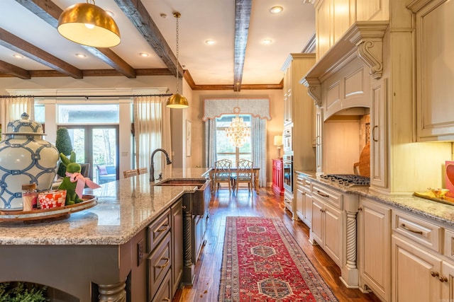 kitchen with dark hardwood / wood-style floors, beam ceiling, a center island with sink, and pendant lighting