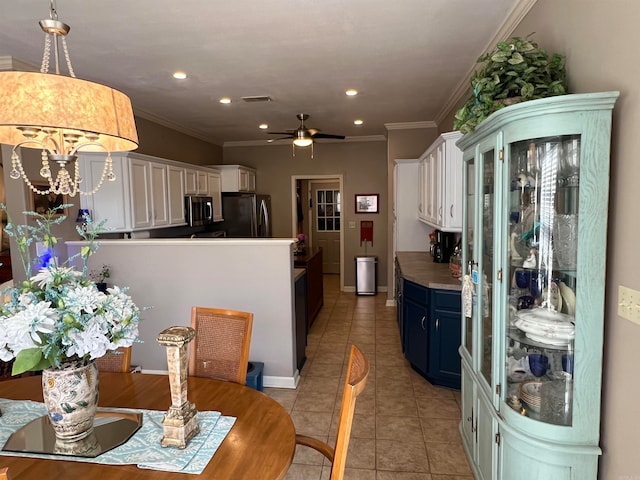 kitchen with appliances with stainless steel finishes, crown molding, white cabinetry, and blue cabinetry