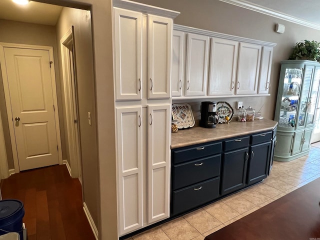 kitchen with ornamental molding, white cabinets, and light hardwood / wood-style flooring