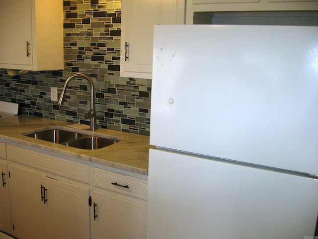 kitchen featuring white fridge, tasteful backsplash, white cabinetry, and sink