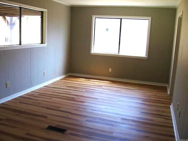 spare room with a healthy amount of sunlight, ornamental molding, and dark hardwood / wood-style floors