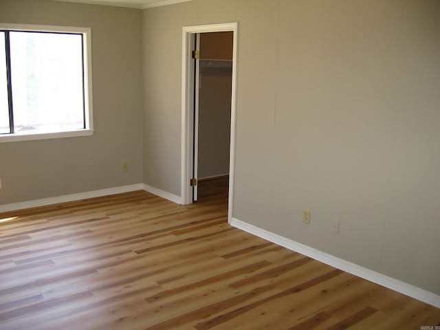 unfurnished bedroom featuring a closet, a walk in closet, and light wood-type flooring