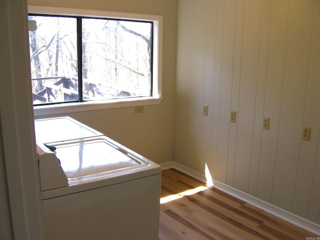 washroom with wood walls, washer and dryer, and light wood-type flooring