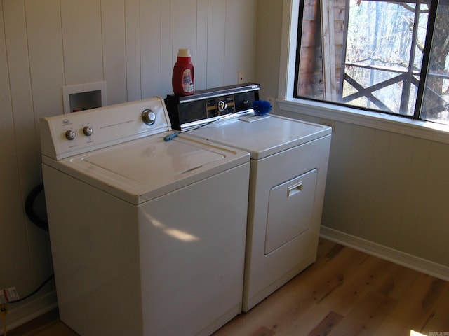 washroom featuring light hardwood / wood-style floors, washer and clothes dryer, and wooden walls