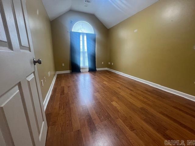 unfurnished room featuring lofted ceiling and wood-type flooring