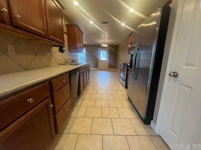 kitchen with light tile patterned floors, stainless steel appliances, sink, and backsplash