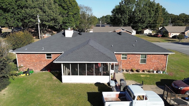 back of property featuring a yard and a sunroom