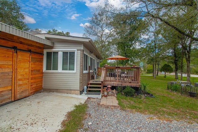 exterior space with a wooden deck, a patio area, and a lawn