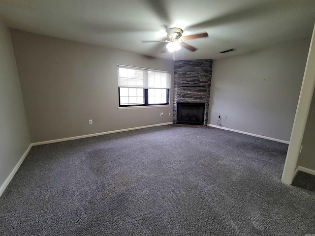 unfurnished living room with dark colored carpet, a ceiling fan, visible vents, and a stone fireplace
