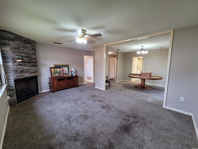 unfurnished living room with a stone fireplace, dark colored carpet, and ceiling fan