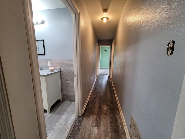 corridor with tile walls and hardwood / wood-style flooring