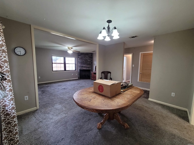 living area with ceiling fan with notable chandelier, visible vents, carpet floors, baseboards, and a stone fireplace