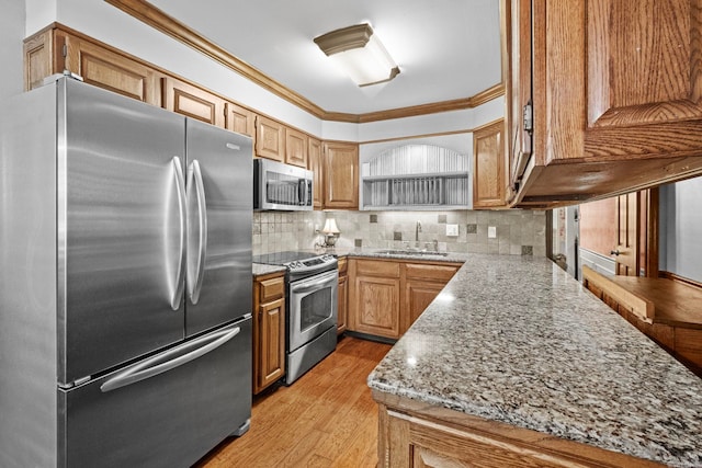 kitchen featuring tasteful backsplash, appliances with stainless steel finishes, sink, crown molding, and light hardwood / wood-style flooring