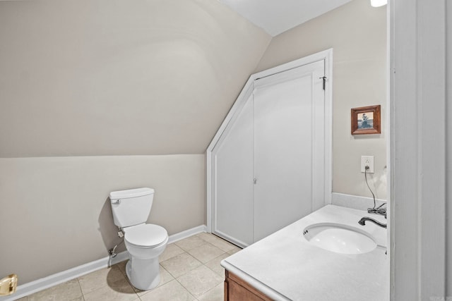 bathroom featuring toilet, lofted ceiling, vanity, and tile patterned floors