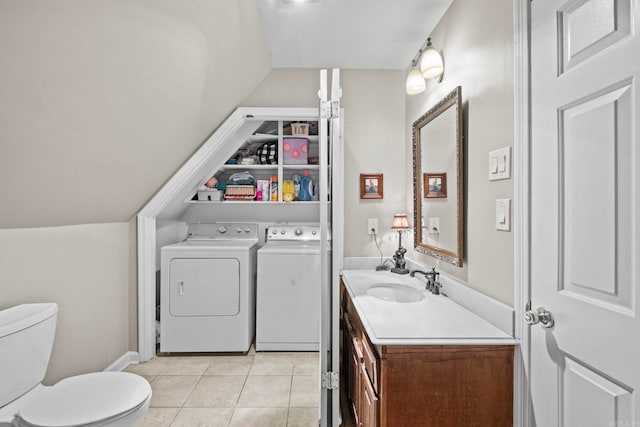 bathroom with toilet, tile patterned flooring, vaulted ceiling, vanity, and washing machine and clothes dryer