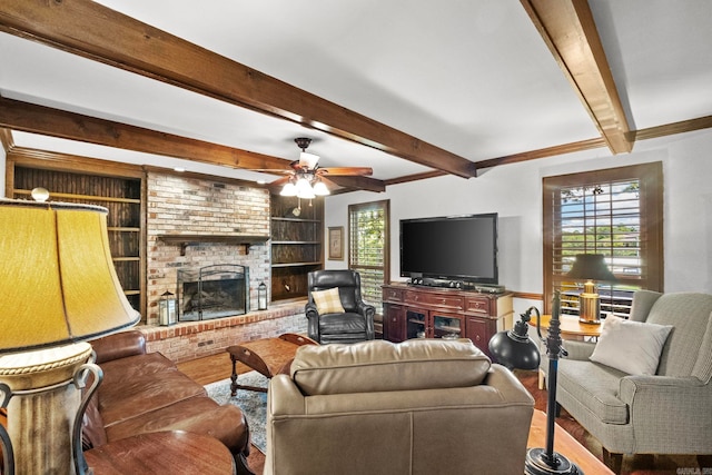 living room featuring ceiling fan, beamed ceiling, a brick fireplace, and hardwood / wood-style floors