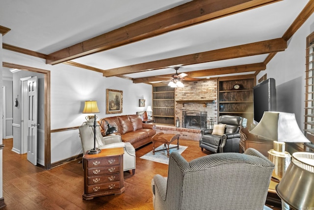 living room with beam ceiling, a brick fireplace, dark hardwood / wood-style floors, built in shelves, and crown molding