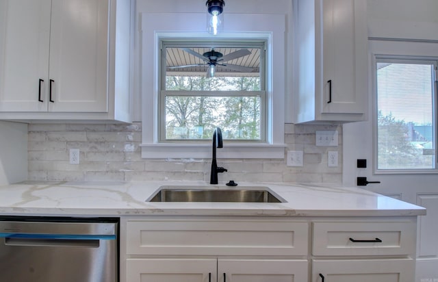 kitchen with decorative backsplash, sink, light stone countertops, stainless steel dishwasher, and white cabinetry