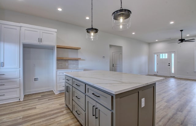 kitchen with light hardwood / wood-style floors, light stone countertops, ceiling fan, and pendant lighting