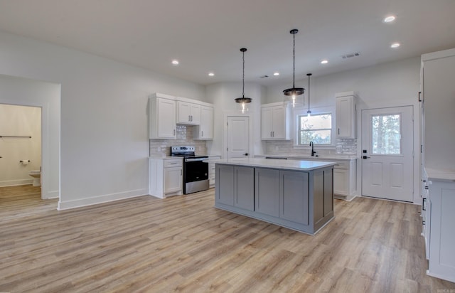 kitchen with decorative backsplash, a center island, light wood-type flooring, white cabinetry, and electric stove