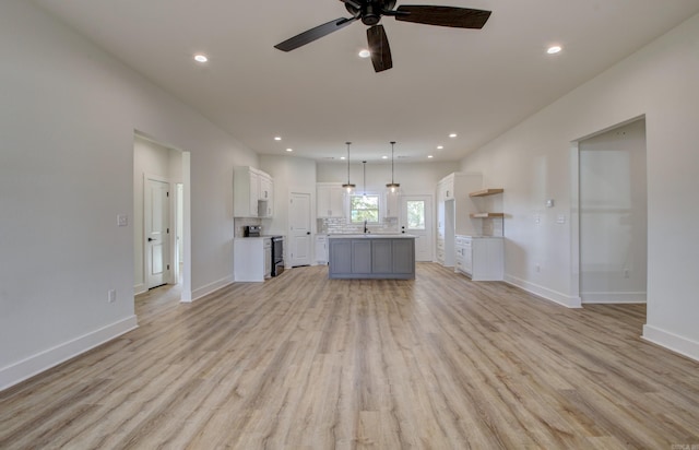 unfurnished living room with ceiling fan, sink, and light wood-type flooring