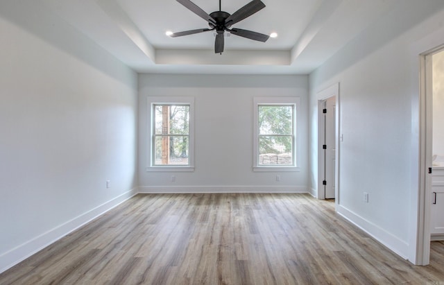 empty room featuring light hardwood / wood-style floors, a raised ceiling, and ceiling fan