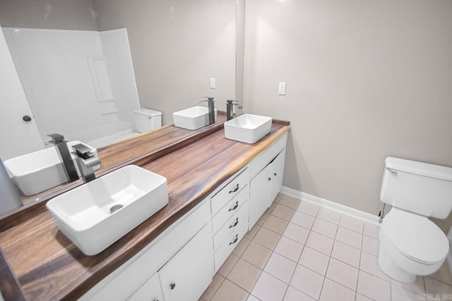 bathroom featuring a washtub, vanity, toilet, and tile patterned floors