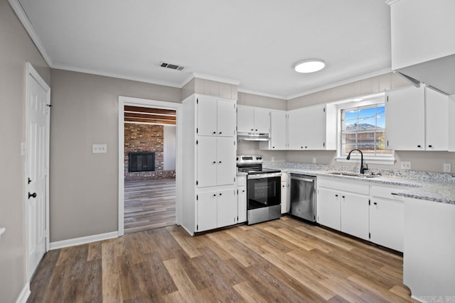 kitchen with sink, white cabinetry, light hardwood / wood-style floors, stainless steel appliances, and ornamental molding