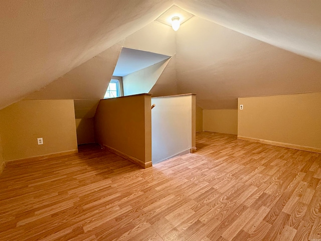 bonus room with light wood-type flooring and lofted ceiling