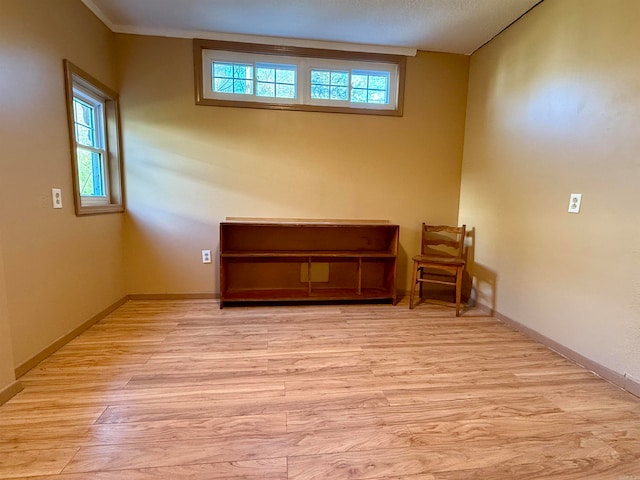 unfurnished room with ornamental molding, a textured ceiling, and light hardwood / wood-style floors