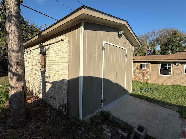 view of side of home with a storage unit, a lawn, and a patio area