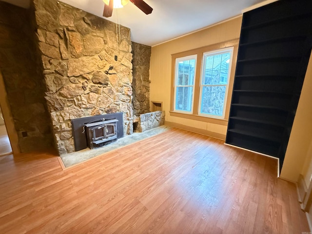 unfurnished living room featuring hardwood / wood-style flooring, ceiling fan, and a wood stove