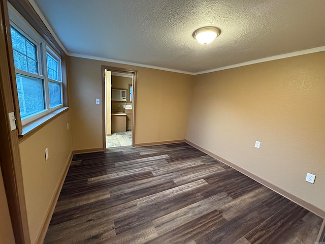 empty room featuring dark wood-type flooring, a textured ceiling, and ornamental molding