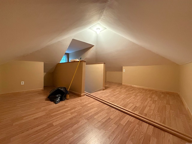 additional living space featuring light wood-type flooring and lofted ceiling