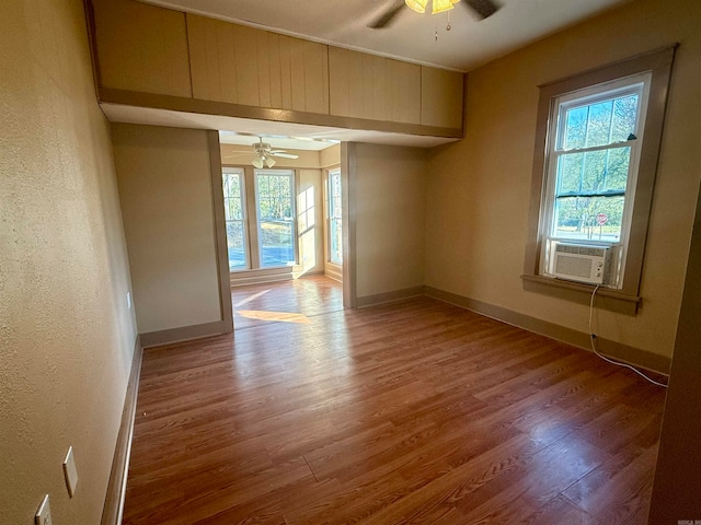 empty room featuring cooling unit, hardwood / wood-style flooring, and ceiling fan