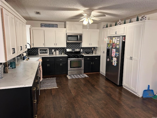 kitchen featuring appliances with stainless steel finishes, white cabinetry, a textured ceiling, and dark hardwood / wood-style floors